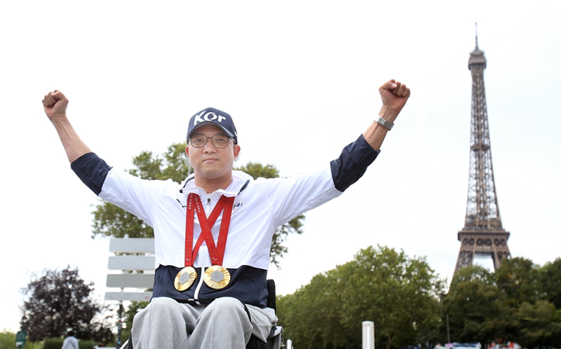 Park Jinho, who won two gold medals in shooting at this year's Paris Summer Paralympics, on Oct. 9 poses wearing his honors with the Eiffel Tower in the background.