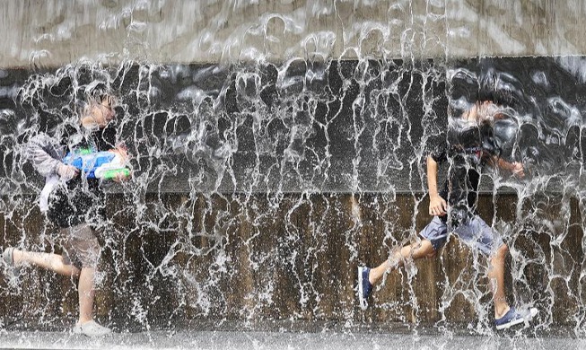 Playing around water fountain amid heat wave